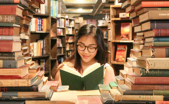 estudiante preocupado revisando libros en biblioteca