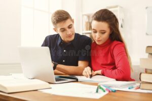 jovenes estudiando con laptops y libros abiertos