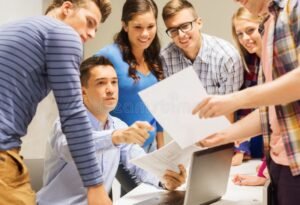 maestro sonriente con papeles y laptop