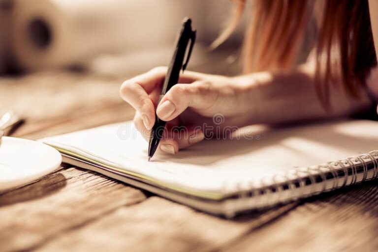 manos escribiendo en cuaderno con pluma
