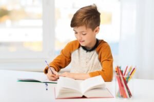 nino escribiendo en cuaderno con lapiz